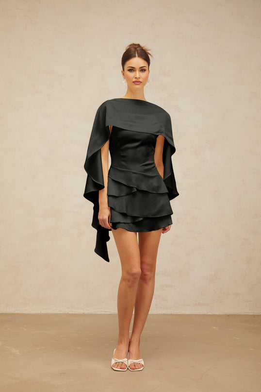 A black satin mini dress with ruffled details and a shawl panel accent