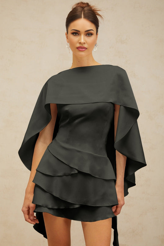 A black satin mini dress with ruffled details and a shawl panel feature worn by a model against a plain background