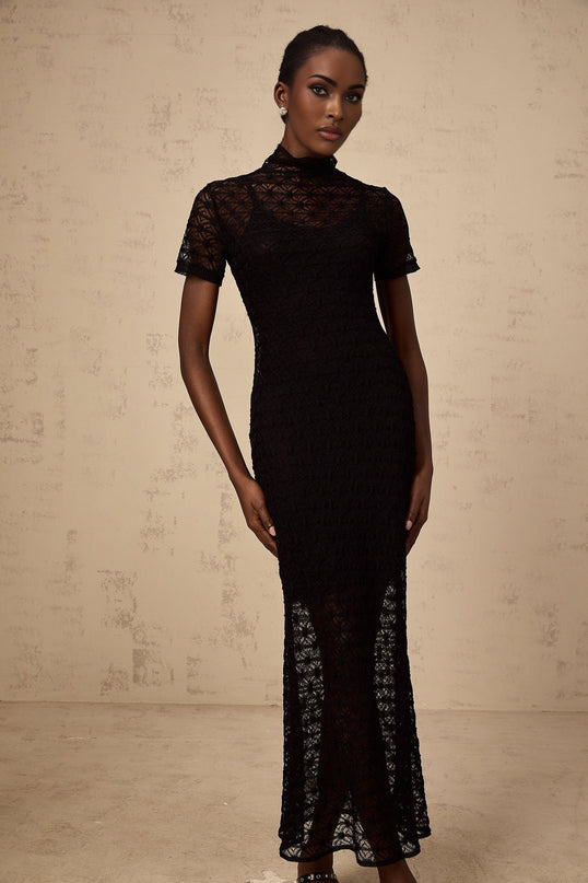 A black semi sheer knit midi dress on a mannequin or model showing the fitted silhouette and see through texture of the fabric