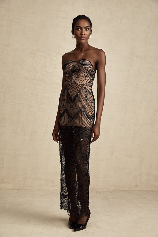 A black sequinned corset dress with a mesh maxi skirt featuring a fitted bodice and long flowy design