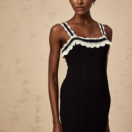 A black sleeveless midi dress with a crochet knit pattern throughout featuring a form fitting silhouette and scoop neckline