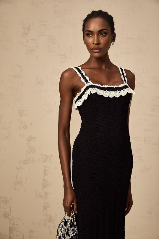 A black sleeveless midi dress with a crochet knit pattern throughout featuring a form fitting silhouette and scoop neckline