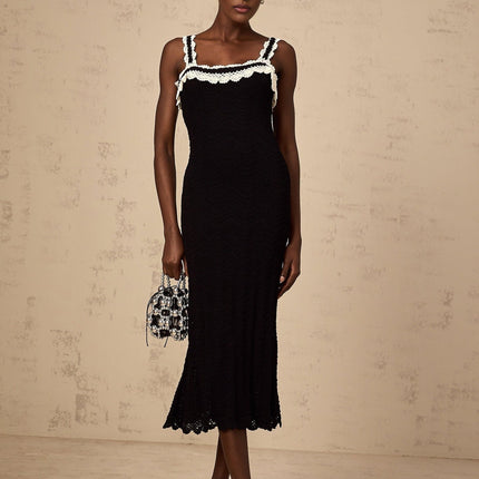 A black sleeveless midi dress with intricate crochet knit detailing throughout the garment