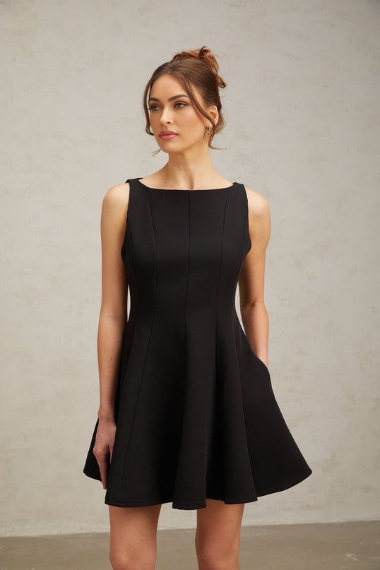 A black sleeveless mini dress with a flared skirt worn by a model against a plain background