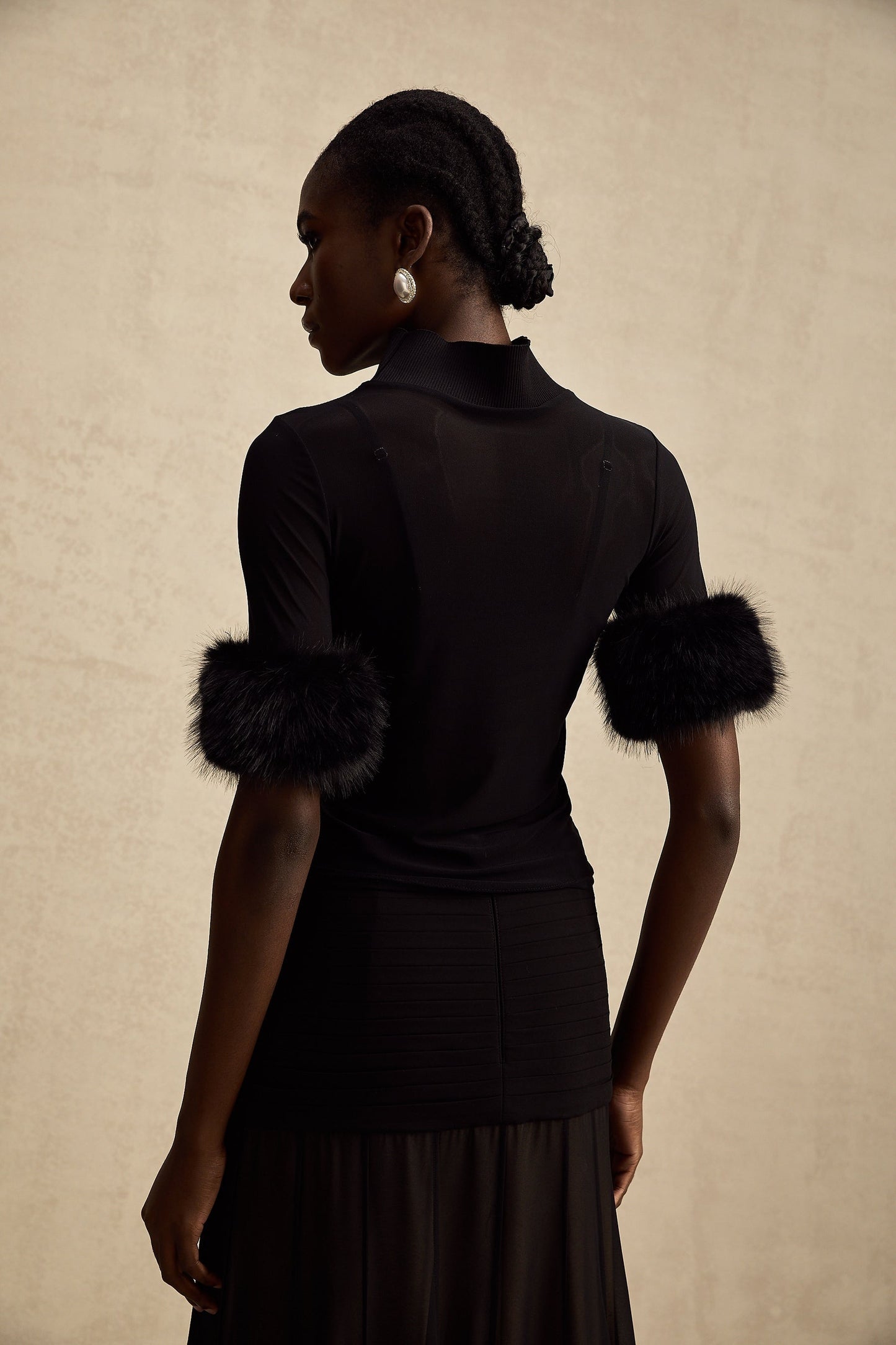 A black sleeveless top with a faux fur bodice and sheer tulle overlay creating a glamorous and elegant look