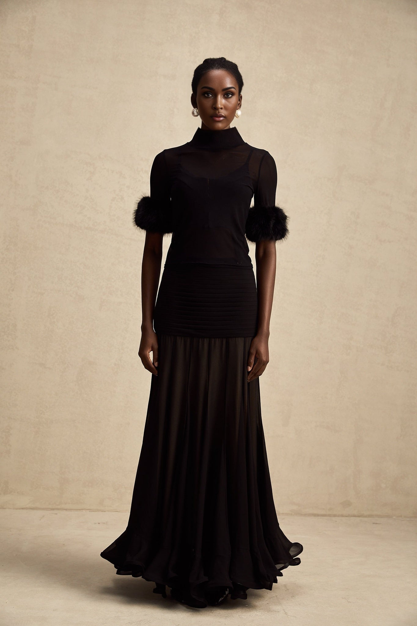 A black sleeveless top with a faux fur bodice and sheer tulle overlay creating a luxurious and elegant look