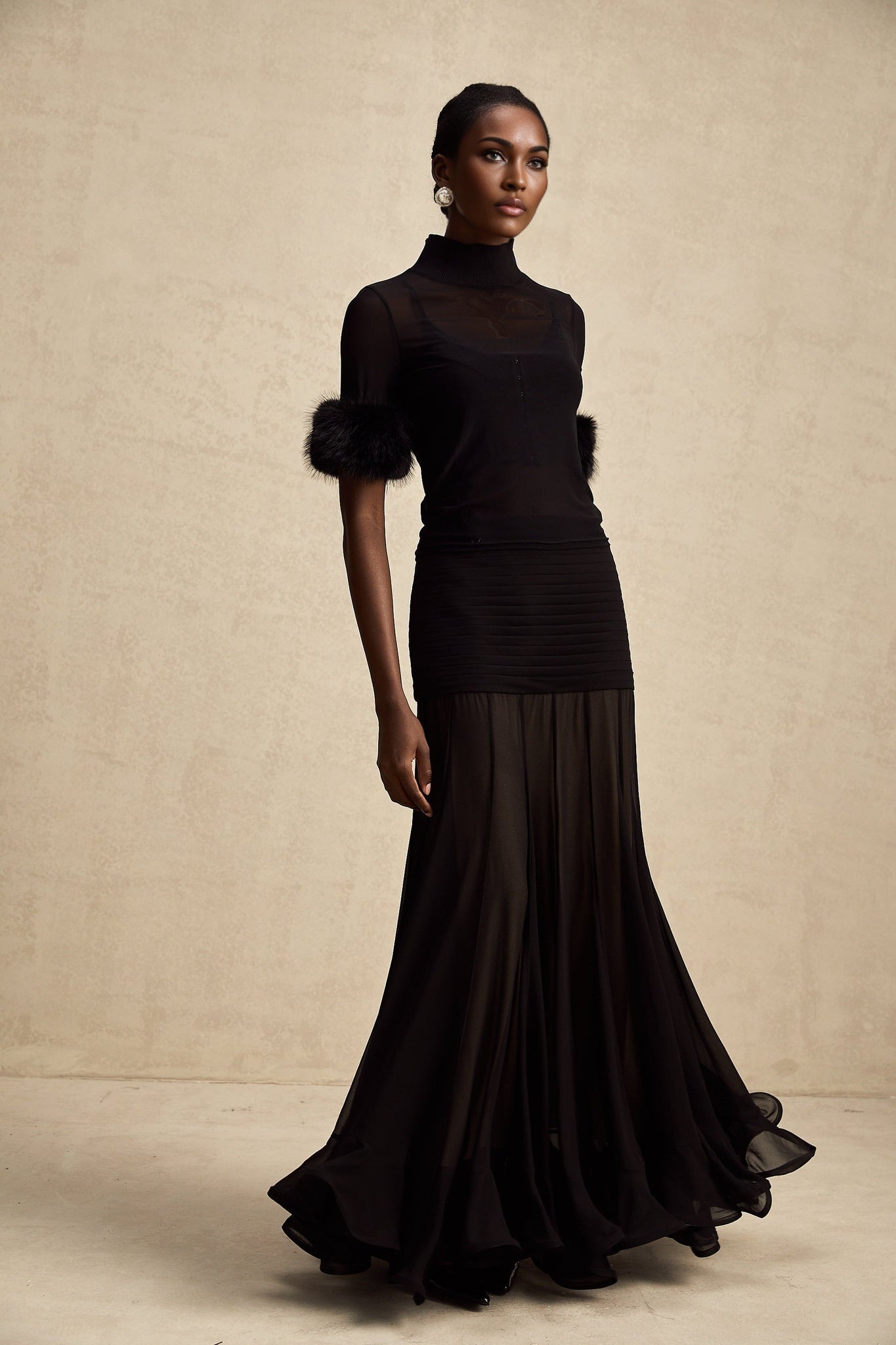 A black sleeveless top with a faux fur bodice and sheer tulle overlay creating a luxurious and elegant look