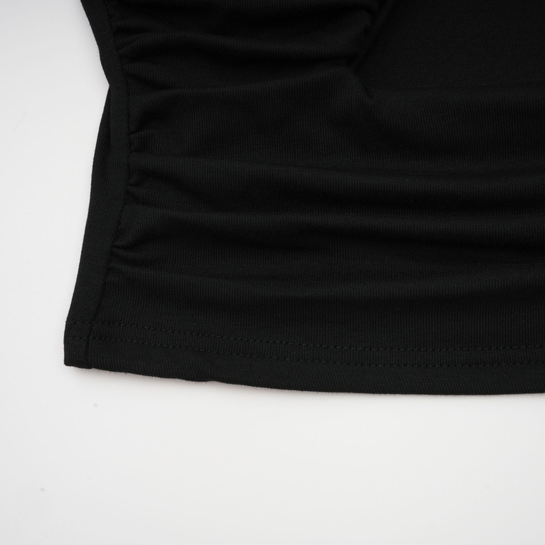 A black sleeveless top with an open front design and gathered fabric detailing