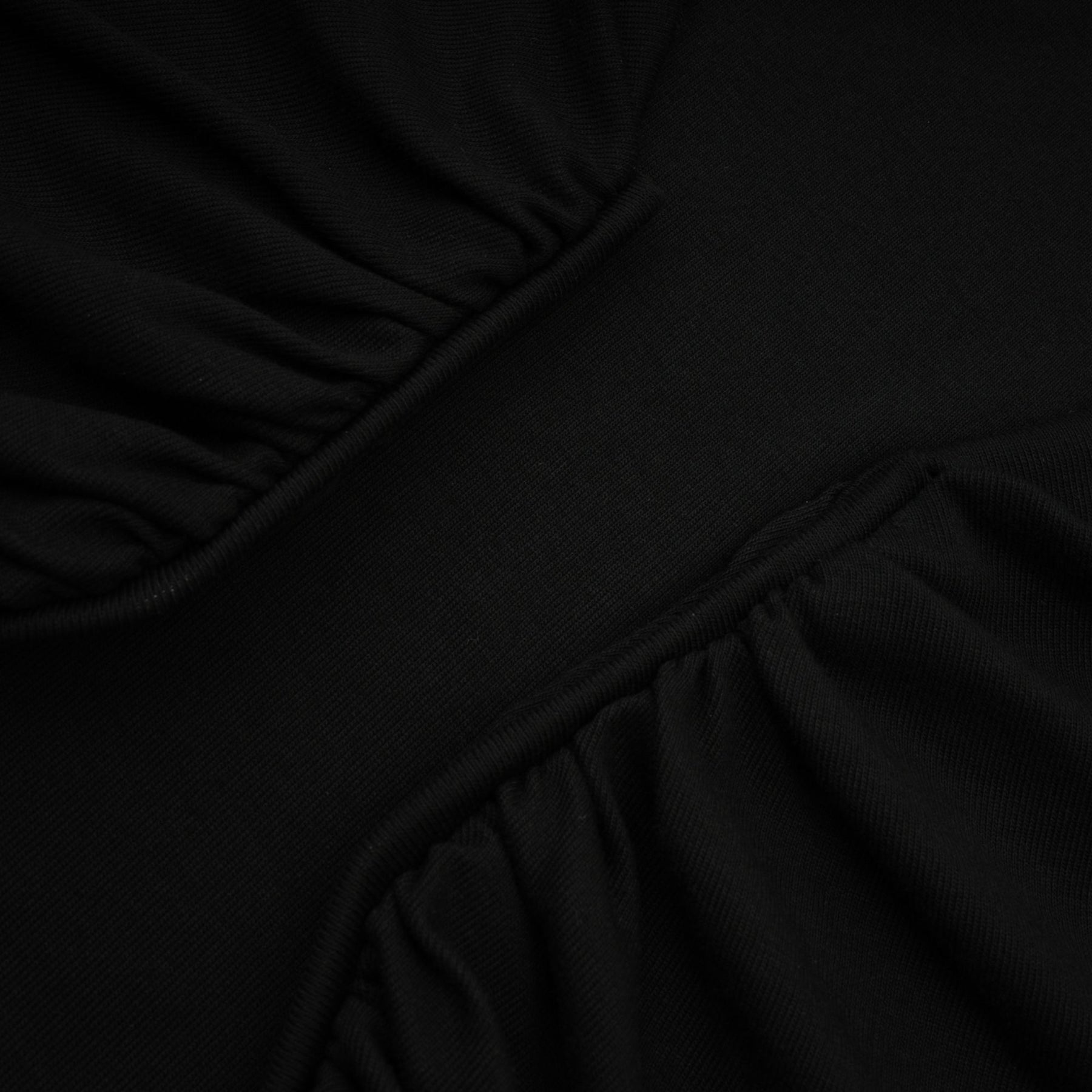 A black sleeveless top with an open front design and gathered fabric details