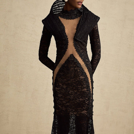 A black structured fishtail maxi dress with a split detail worn by a model standing against a plain background