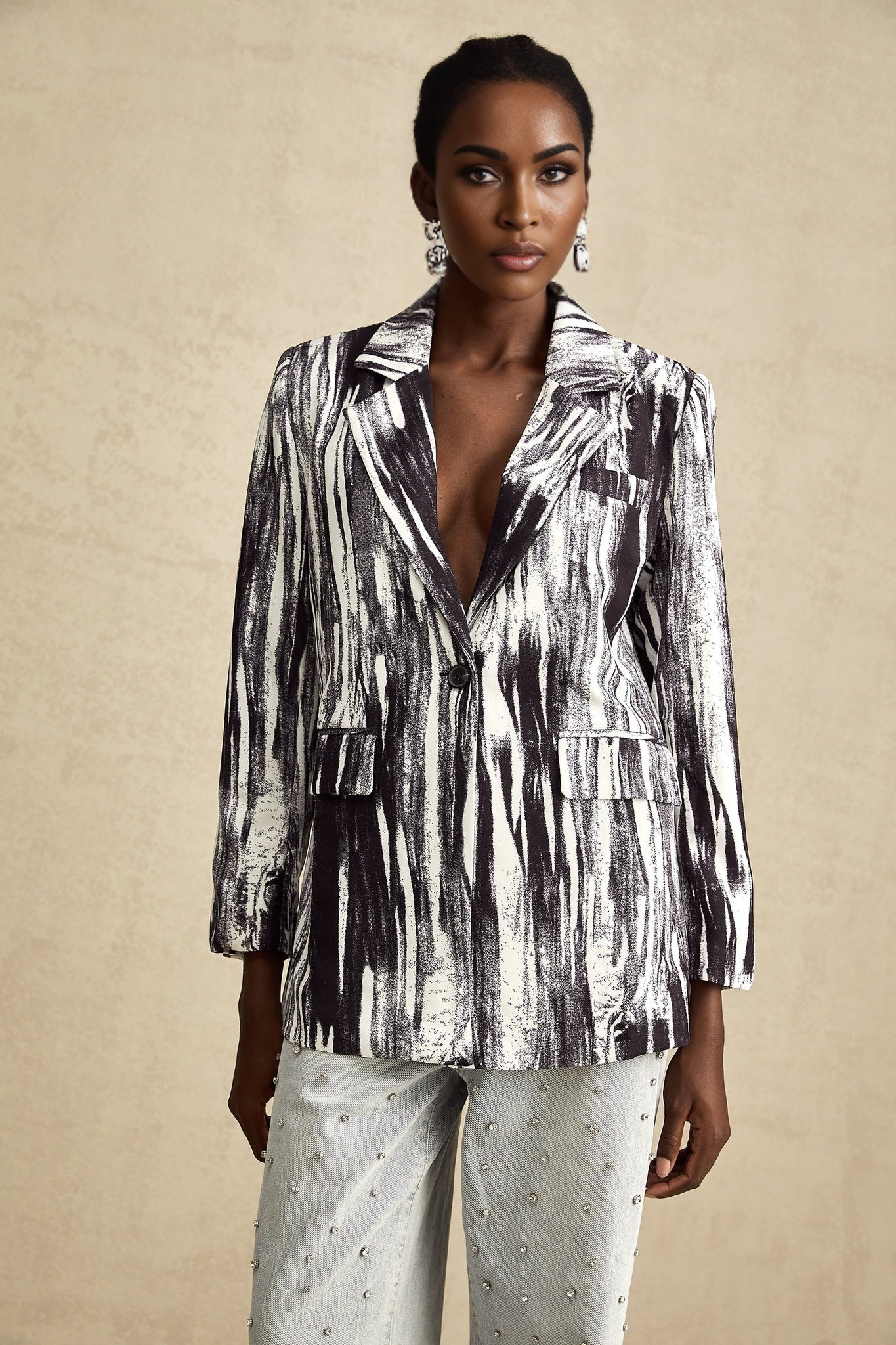A black textured jacket with graffiti style print covering the surface worn by a model against a plain background