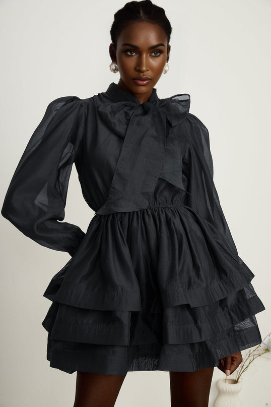 A black tiered flared mini dress with ruffled layers creating a voluminous silhouette