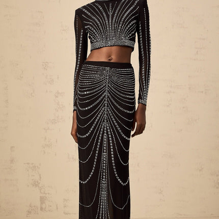 A black twopiece outfit consisting of a mesh top and skirt adorned with rhinestones The top is sleeveless with a high neckline The skirt is short and fitted Both pieces feature a sheer mesh material with sparkling rhinestone embellishments throughout
