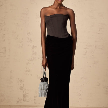 A black velvet maxi dress with an offshoulder neckline and long skirt worn by a model against a plain background