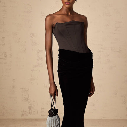 A black velvet maxi dress with an offshoulder neckline worn by a model standing against a plain background