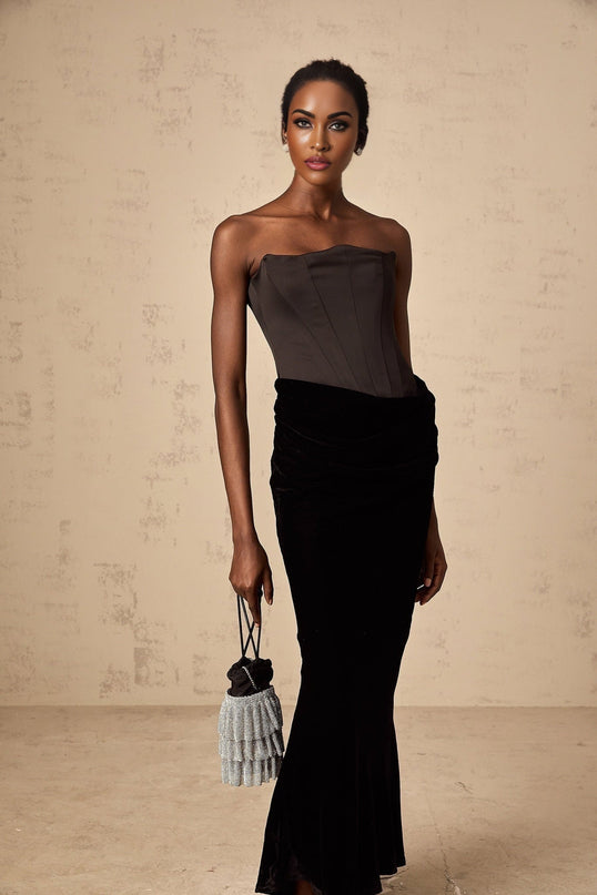 A black velvet maxi dress with an offshoulder neckline worn by a model standing against a plain background