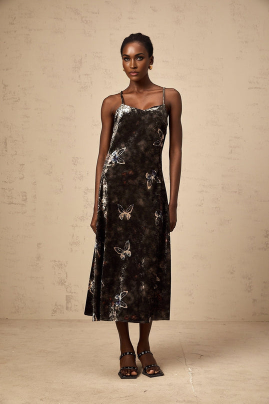 A black velvet midi dress with a butterfly print pattern featuring long sleeves and a fitted silhouette