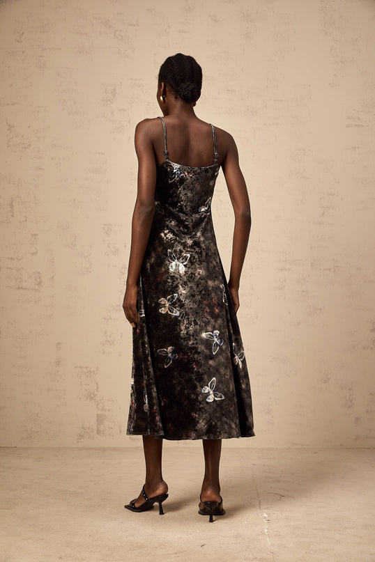A black velvet midi dress with a butterfly print pattern featuring long sleeves and a flared skirt