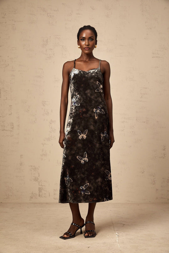 A black velvet midi dress with a butterfly print pattern featuring long sleeves and a flowing silhouette