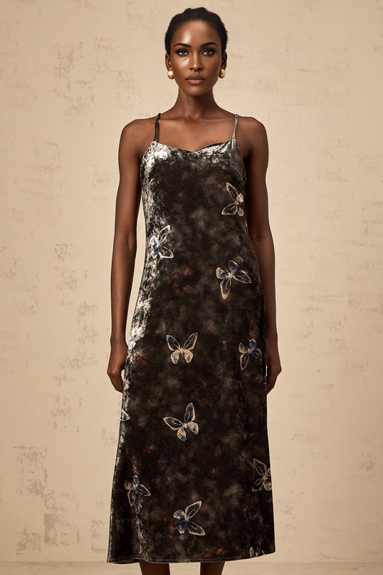 A black velvet midi dress with butterfly print pattern worn by a model against a plain background