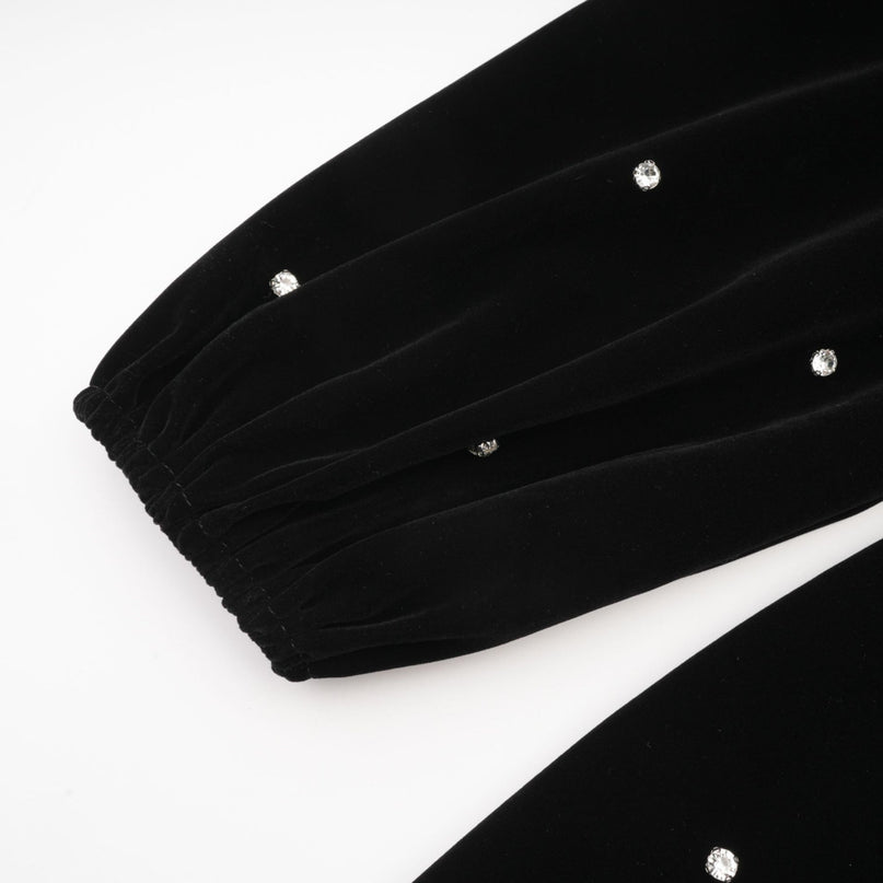 A black velvet midi dress with embellishments named Lola featuring a sleek silhouette and luxurious texture