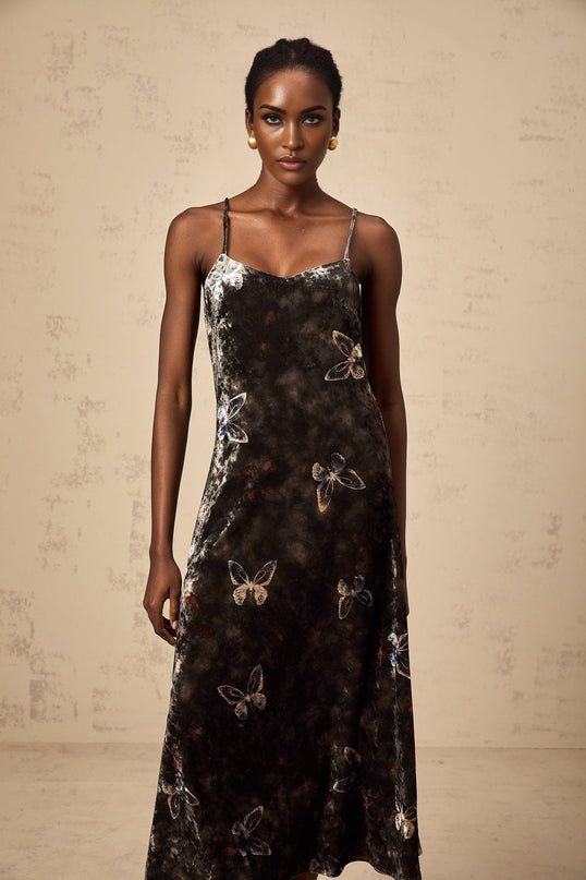 A black velvet midi dress with white butterfly print pattern covering the fabric The dress features long sleeves and a fitted silhouette reaching just below the knee