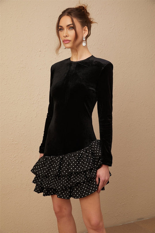 A black velvet mini dress with polka dot print featuring ruffled panels and a short hemline