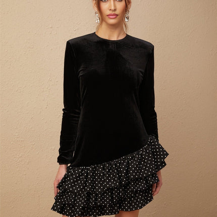 A black velvet mini dress with white polka dots featuring ruffled panels and a flared skirt