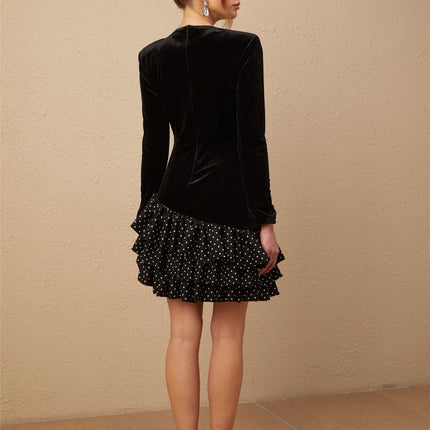 A black velvet mini dress with white polka dots featuring ruffled panels and a short hemline