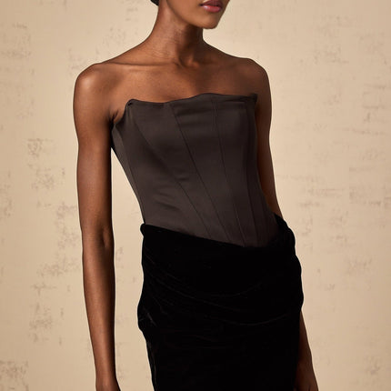 A black velvet off shoulder maxi dress with a long flowing skirt worn by a model against a plain background