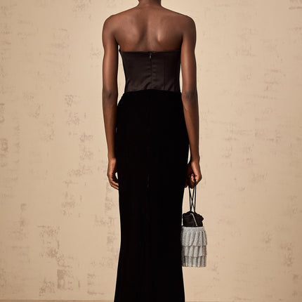 A black velvet offshoulder maxi dress with a long flowing skirt worn by a model