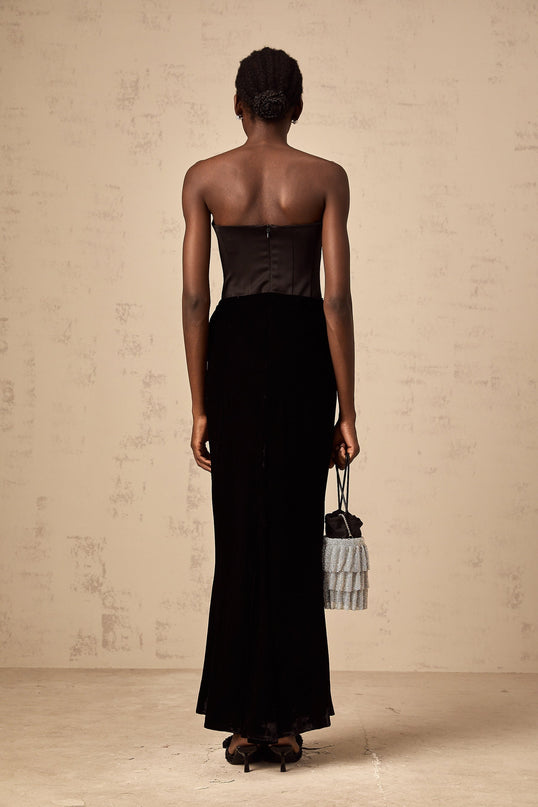 A black velvet offshoulder maxi dress with a long flowing skirt worn by a model