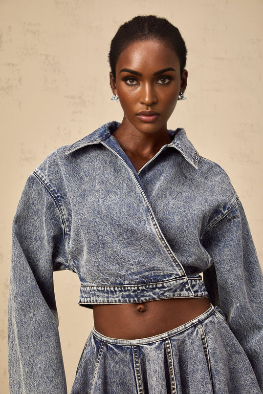 A blue cropped denim jacket with an asymmetrical design featuring a distinctive cut and style named Doriane