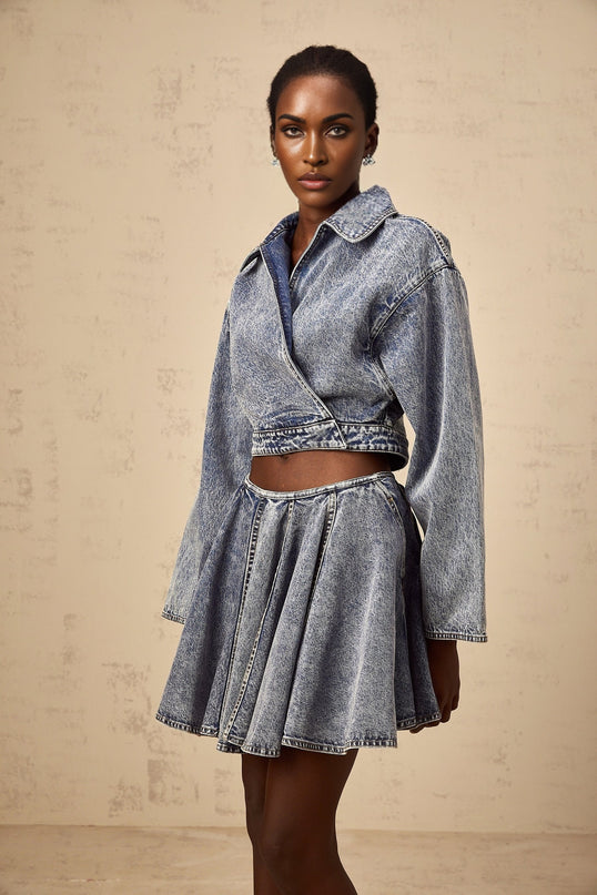 A blue cropped denim jacket with an asymmetrical design featuring the name Doriane