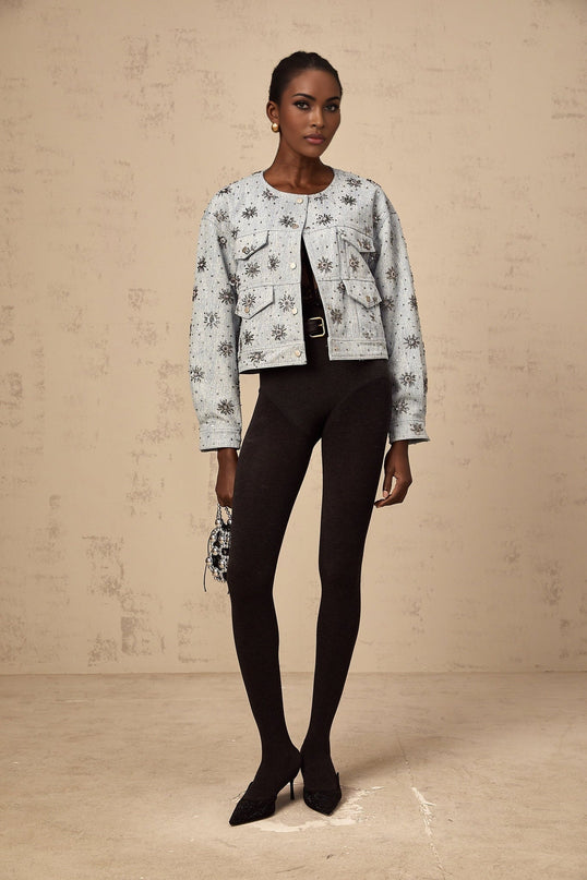 A blue denim jacket with studded sun designs decorating the fabric featuring a distressed look and classic collar