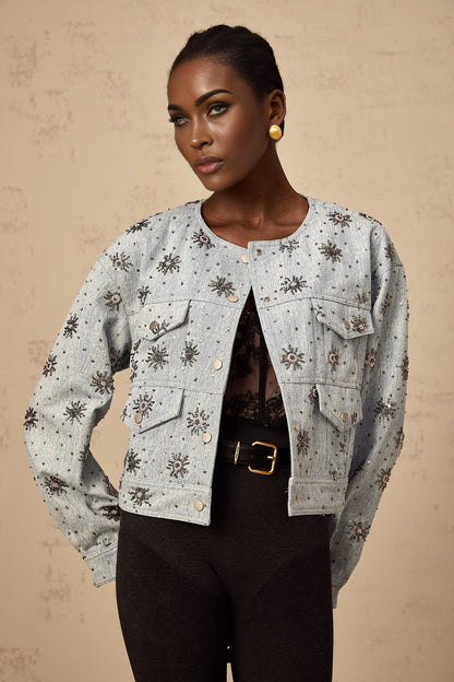 A blue denim jacket with studded sun motifs and decorative embellishments featuring a distressed look and visible stitching details