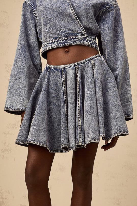 A blue denim mini skirt with shirred detailing named Doriane shown on a plain background