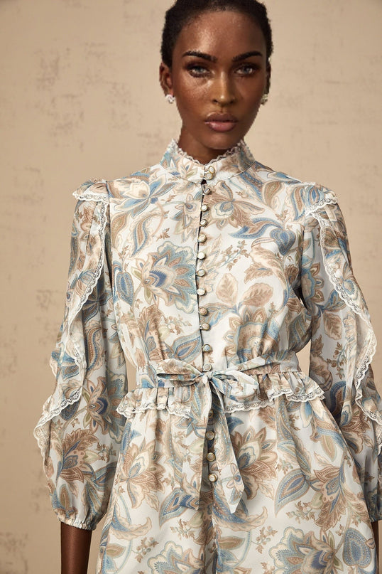 A blue floral print jumpsuit with ruffles and lace trim details named Eugenie