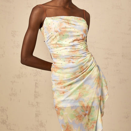 A blue maxi dress with an asymmetric design featuring a floral print pattern and ruched detailing