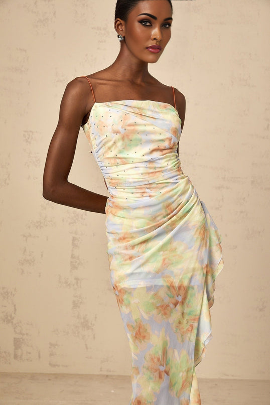 A blue maxi dress with an asymmetric design featuring a floral print pattern and ruched detailing