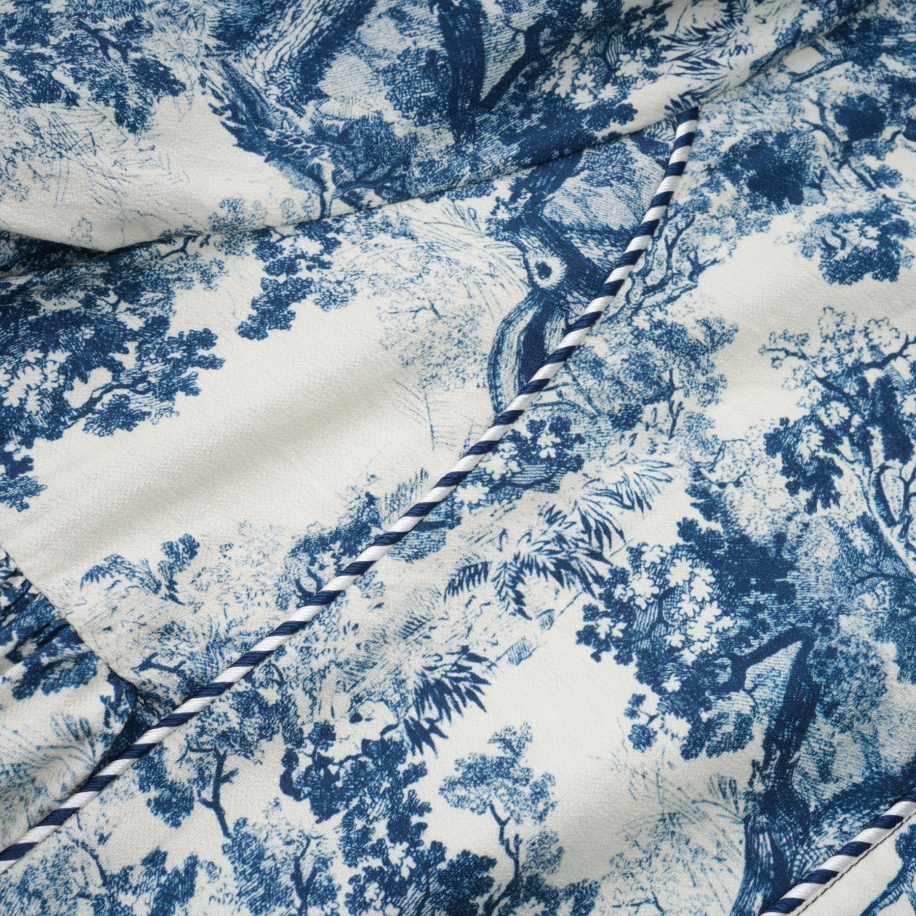 A blue midi dress with a graphic print pattern featuring the Adélaïde design worn by a female model standing against a plain background