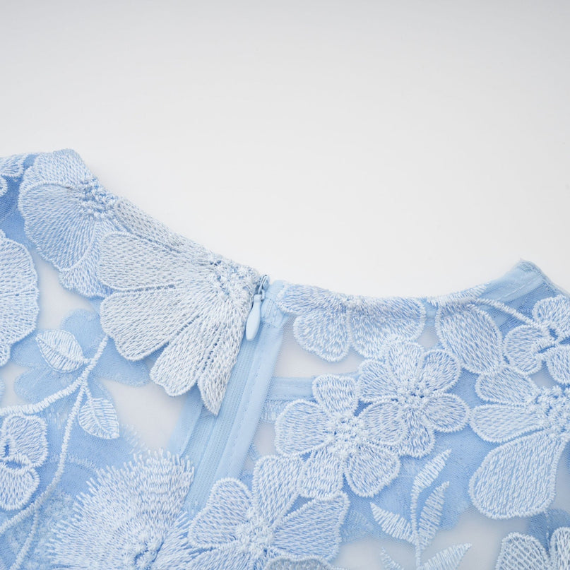 A blue midi dress with floral applique details featuring the Herta design