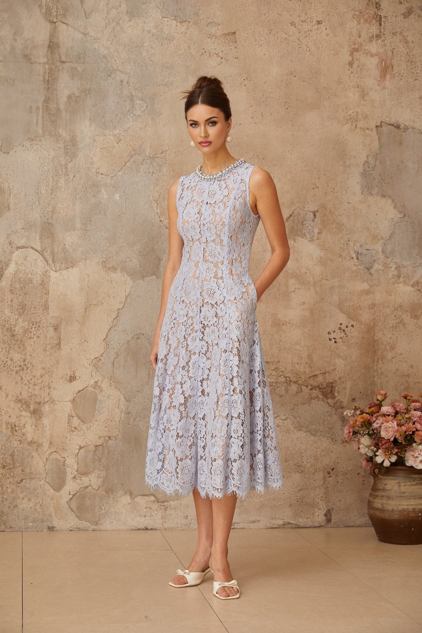 A blue midi dress with floral lace pattern and embellishments featuring a fitted silhouette and delicate details