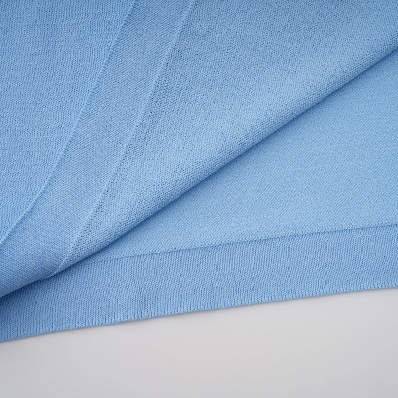 A blue midi dress with ruffled trim and crochet knit detailing worn by a model standing against a plain background