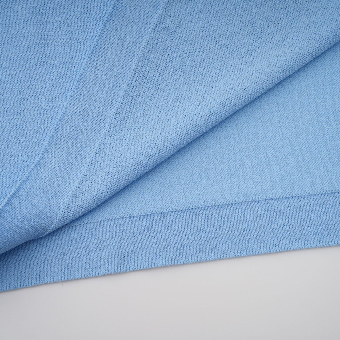 A blue midi dress with ruffled trim and crochet knit detailing worn by a model standing against a plain background