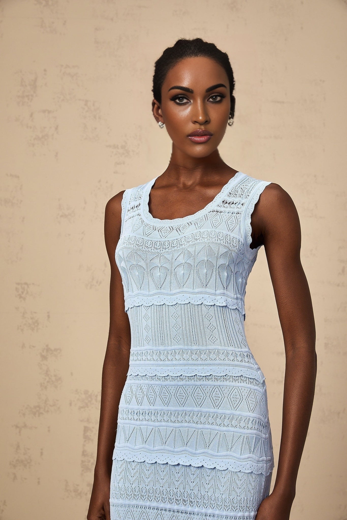 A blue midi dress with ruffled trim and crochet knit pattern featuring a feminine silhouette and delicate texture