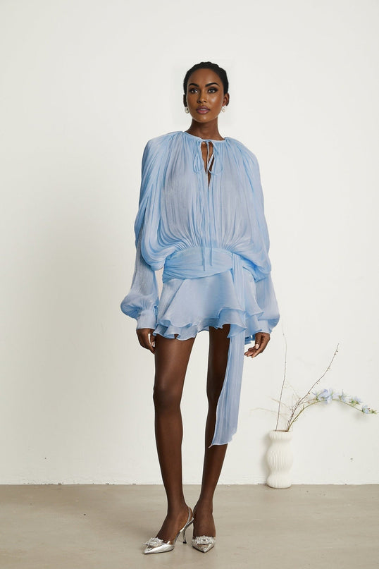A blue mini dress with full pleats and ruffled details named Eugenie