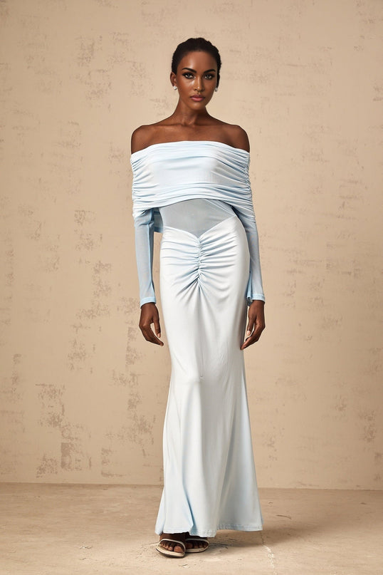 A blue offshoulder maxi dress with ruched detailing named Ninon worn by a model against a plain background