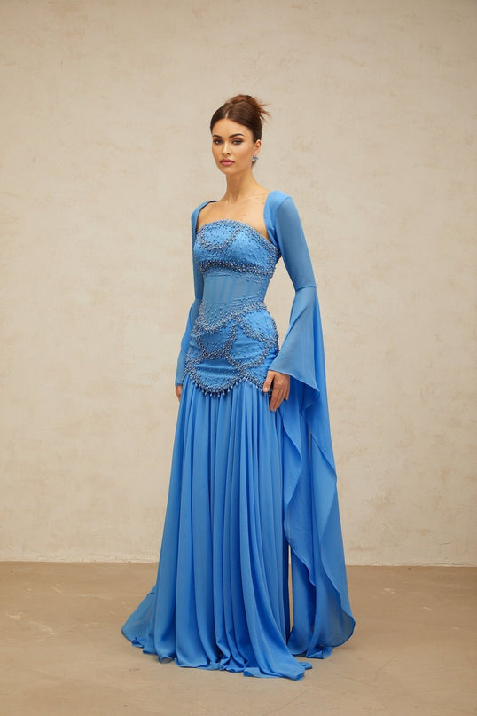 A blue pleated maxi dress with faux pearl embellishments by Gaelle