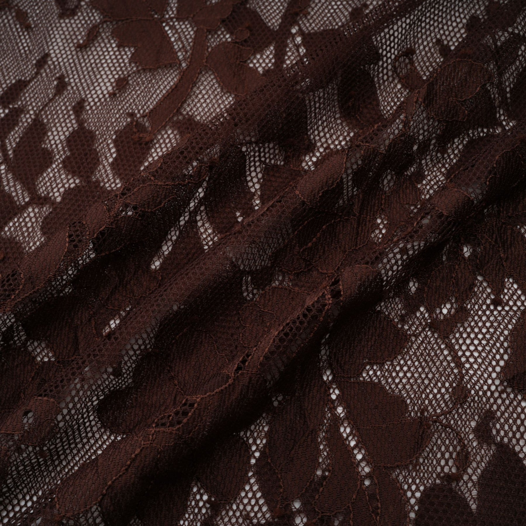 A brown flared midi dress made of chantilly lace named Sylvie featuring delicate floral patterns and a feminine silhouette